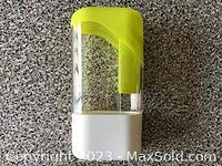 View of transparent herb keeper container with white base and bright green lid on granite surface.