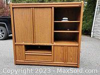 Full view of the oak cabinet showing vertical tambour door, drawers, cupboard doors and open shelving.