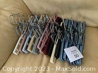 Photo showing 18 pant hangers in various colors arranged on a couch.