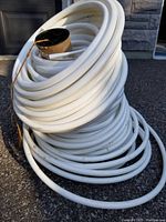 Large spool of white 1/2 inch water hose coiled on cardboard core, showing thickness and condition.