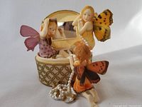 Jewelry box with three fairy figurines and pearls arranged around it
