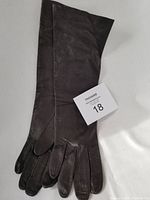 Photo showing the full length brown leather gloves with visible fine finger stitching and long cuffs.