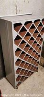 Full view of wine rack with diamond compartments, leaning against wall.
