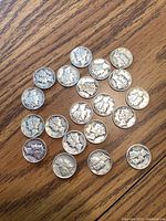 20 Mercury dimes arranged loosely on a wooden surface, obverse side showing Liberty profile with winged cap.
