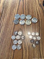 Top view of 7 Bicentennial half dollars (dual date 1776-1976) arranged in two rows on a wooden surface, silver color, all showing some wear and patina.