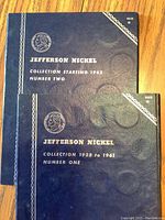 Two blue coin collector books for Jefferson Nickels, with white embossed text and profile image. Covers show wear and texture details.