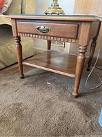 Wooden Ethan Allen side table showing front drawer and turned legs.