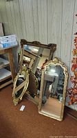 Three decorative mirrors leaning against wall, showing size and frame details