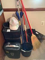 Group photo of storage bins, cleaning tools including broom, rake, grabbers, bucket, and hats.