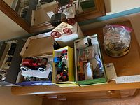 Overview of the lot showing toy model cars, a box with assorted smaller cars, Hard Rock Cafe pins in a plastic bag and tin on a wooden surface.