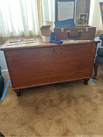 Front view of vintage wooden chest showing lock area and ball feet.