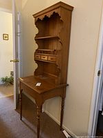 Full view of the freestanding wooden hutch secretary desk showing two open shelves above a lift-top writing surface and four supporting legs