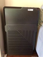 Front view of black rectangular air purifier with vented grill design on lower front panel.