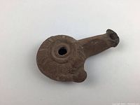 Top view of the ancient terracotta oil lamp showing the circular opening and decorative patterns around it.