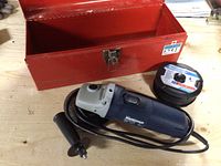 Mastercraft 4.5 inch angle grinder, cut-off wheel set, black side handle, and red metal case open on wooden surface.