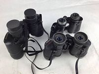 Photo showing three binoculars arranged on a white surface, displaying different models and designs