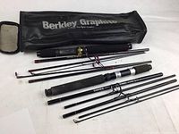 Photo showing two fishing rods disassembled with carrying case: Berkeley Graphite 6-piece fly/spin combo with black carrying case, and Daiwa graphite rod with black foam grip and silver reel seat, all sections laid out.