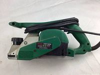 Side view showing green plastic housing with Craftsman label, cord coiled on handle.