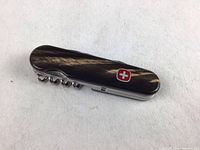 Wenger Swiss Army multi-tool closed, showing cow horn handle with Swiss cross emblem and corkscrew visible.