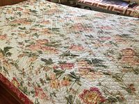 Quilt spread out on a bed showing full floral design atop surface.