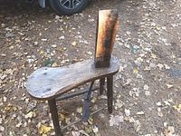 Full view of the antique wooden stitching horse showing the curved seat and clamp mechanism.