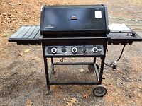 Full front view of the black Napoleon propane gas barbecue grill with side shelves and four control knobs on the front.