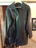 Full front view of vintage Daniel black leather men's coat on hanger, showing smooth leather, slant pockets, and front zipper.