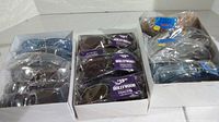 Multiple boxes of new sunglasses in different styles, mostly individually wrapped with tags showing $12.95 Hollywood Pyramid Optics branding.