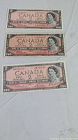 Front sides of the three 1954 Canadian two dollar bills showing Queen Elizabeth II portrait and denomination markings.