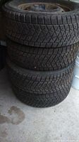 Stack of four Blizzak snow tires on rims with visible tread and rust on rims