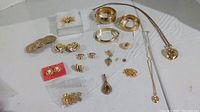 Overview of the full set of 17 gold-toned jewelry pieces laid out on a white surface, showing all different items together.