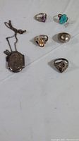 All five rings and one chain with locket laid out showing overall condition and variety.