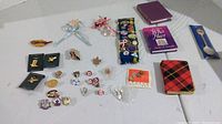 Overview of pins, mini books, and collector spoon laid out on a flat surface