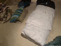 White tufted comforter folded on floor with two decorative pillows nearby