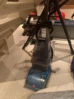 Photo of Hoover SpinScrub 50 carpet cleaner in blue color with clear water tank and accessories.