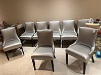 Eight matching silver dining chairs arranged in a basement room, showing overall set condition.