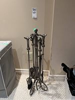 Full view of fireplace tool set with stand including shovel, brush, poker, and tongs, showing metal construction and hooks for hanging.
