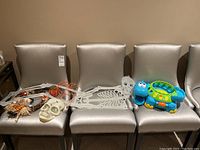 Wide shot of Halloween decorations on four silver chairs including skeleton debris, skull, skeleton wreath, pumpkin decoration, and hippo toy.