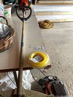 Full length view of the Husqvarna 125 L gas trimmer showing loop handle and the shaft with some wear.