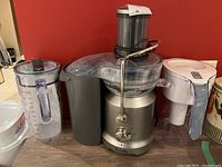 Photo of Breville juicer showing base, control knob, food pusher, and parts