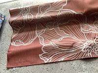 Close-up image of the rust-orange outdoor carpet showing white floral patterns on textured material.