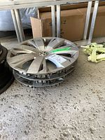 Four stacked Volkswagen hubcaps on concrete floor, showing edges and tops with visible wear and scratches.