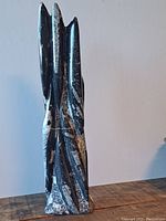 Front view of tall Orthoceras fossil sculpture showing polished black stone with white fossil imprints