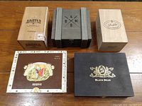 Five wooden cigar boxes arranged side by side showing different brand names and styles.