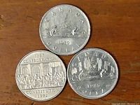 Front sides of three Canadian one dollar coins showing designs from 1980, 1982, and 1985.