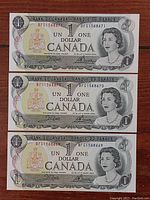 Front side of three Canadian one dollar bills with sequential serial numbers BFG1568671, BFG1568670, BFG1568669 showing Queen Elizabeth II portrait and Bank of Canada markings.