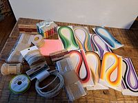 Photo showing the full lot of crafting supplies including colored quilling strips, natural burlap trim rolls, ribbons on spools, and jute twine.