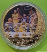 Gold plated commemorative coin side featuring Kobe Bryant with five NBA championship trophies in color photo