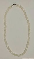 Full view of double strand mother of pearl necklace with metal clasp, laid flat on white surface