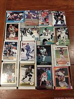 Photo showing a selection of sports cards laid out face up including hockey, basketball, football, and baseball cards with varying images and borders.
